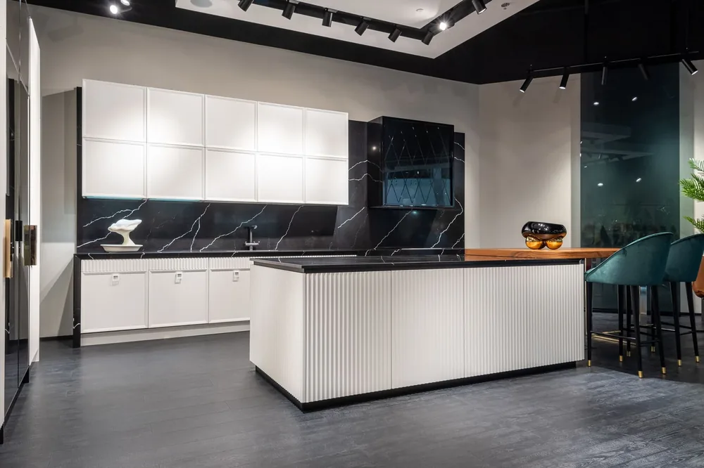 A handleless white kitchen with a dark stone island