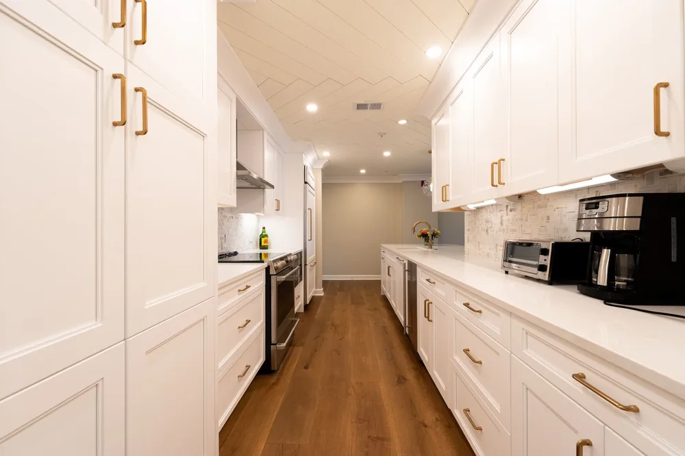 A long white shaker galley kitchen with brass handles